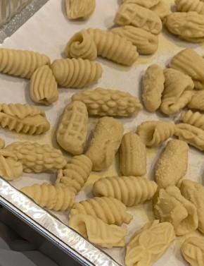 Raw rolled cavatelli pasta dough, laying on a white sheet pan